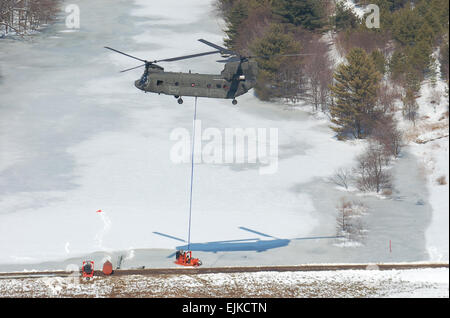 Un esercito di Maryland Guardia Nazionale CH-47D elicottero Chinook dalla società B, 3° Battaglione, 126Reggimento di aviazione, assiste le autorità locali da traino due giganti le pompe utilizzate per alleviare la pressione su una diga in Western Maryland città di Oakland il 7 marzo. La diga ha avuto diventare pericolosamente piena quando sommerso tubo di efflusso era divenuto ostruito con bastoni e fango poste dai castori. Foto Stock