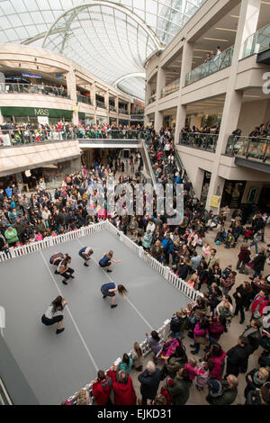Gli amanti dello shopping e una strada performer dancing in Trinity shopping centre, Leeds Foto Stock