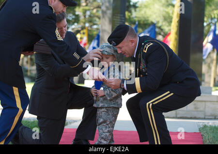 Da sinistra il comando Sgt. Il Mag. Jim Thomson, Kansas Gov. Sam Brownback, e 1a Divisione di Fanteria Comandante Generale Il Mag. Gen. William Mayville presente un medaglione a Michael Cook Jr. III durante un 9/11 cerimonia di commemorazione a Fort Riley, Kan., domenica. Cuocere il padre morì servendo con la divisione di seconda brigata pesante Team di combattimento in Iraq questo giugno. Sgt. Roland Hale, 1INF. Div. Affari pubblici Foto Stock