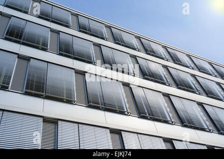 Facciata del moderno ed alto edificio di uffici con coperte windows veneziane contro il cielo blu Foto Stock