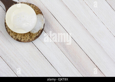 Alta angolazione di una saponata. barra di sapone su una spazzola scrub. Su di un legno rustico superficie la spazzola e sapone sono nella parte superiore sinistra corne Foto Stock