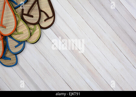 Estate sandali su un rustico di legno bianco superficie. I flip-flop sono impostati nel lato superiore sinistro e angolo del telaio Foto Stock