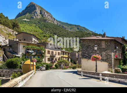 Road, case rurali e di montagna su sfondo sotto il cielo blu nella piccola città di tenda, Francia. Foto Stock