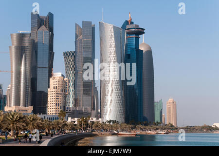 I pedoni a piedi lungomare Corniche, al di sotto di grattacieli, nella città di Doha nel golfo Stato del Qatar. Foto Stock