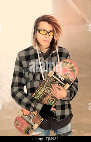 Ritratto di giovane ragazzo con lo skateboard e capelli rasta in un concetto di stile di vita caldo filtro applicato Foto Stock