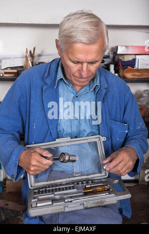 Lavoratori anziani con cricchetto e strumenti in officina. Foto Stock