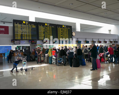 La coda dei passeggeri e dei bagagli del volo charter dell'aeroporto attendono al terminal dell'aeroporto per il check-in dei bagagli per il volo in Spagna Foto Stock