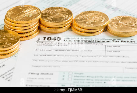 Oro massiccio eagle monete su USA forma fiscale 1040 per l'anno 2014 che illustra il pagamento delle imposte sui moduli per il IRS Foto Stock