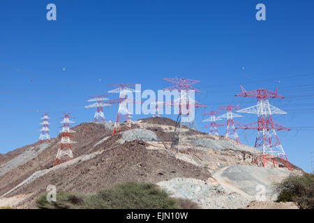 Alta tensione poli di potenza sulla cima di una montagna. Fujairah, Emirati Arabi Uniti Foto Stock