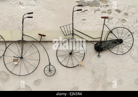 Una bicicletta e un Penny Farthing per vendita e appeso a una parete in St Martin de Re, Ile de Re, Francia. Foto Stock