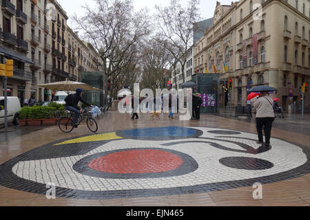 La gente sulla giornata piovosa a piedi lungo Las Ramblas e Joan Miro mosaico, Barcellona, in Catalogna, Spagna Foto Stock