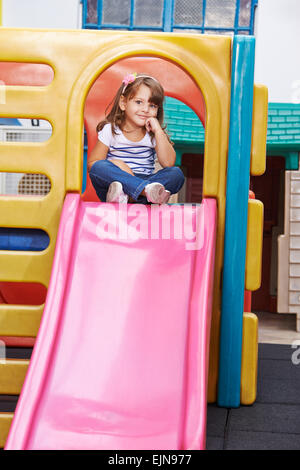 Felice bambino seduto sorridente sulla parte superiore di una diapositiva Foto Stock