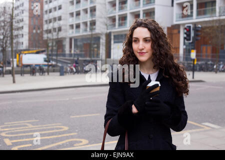 Giovane donna in strada con un caffè Foto Stock