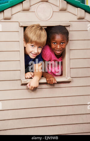 Due bambini felici guardando insieme attraverso una finestra in una playhouse Foto Stock