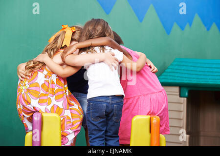 I bambini in una scuola materna di andare in huddle per tenere un consiglio di guerra Foto Stock