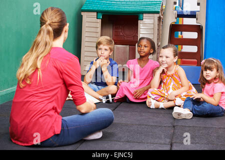 Gruppo di discussione dei bambini nella scuola materna di parlare al vivaio insegnante Foto Stock
