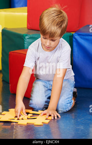 Ragazzo giocando con un grande puzzle in kindergarten Foto Stock