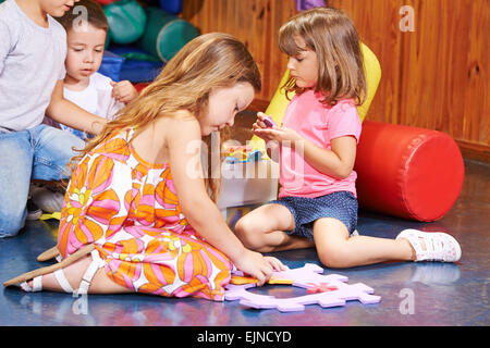 Bambini che giocano insieme in età prescolare con un grande puzzle Foto Stock