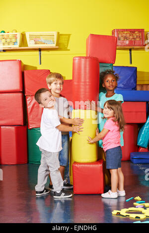 Dei bambini felici giocando insieme in una palestra di un asilo infantile Foto Stock