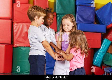 Molti bambini stacking le loro mani in asilo nido palestra Foto Stock