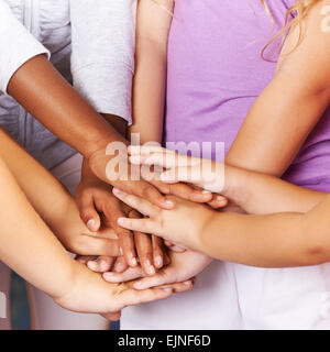 Molti bambini mani di impilamento come simbolo per il lavoro di squadra e di motivazione Foto Stock