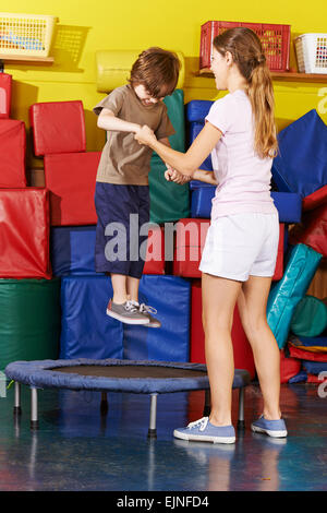 Felice ragazzo di saltare sul trampolino nella scuola materna in palestra Foto Stock