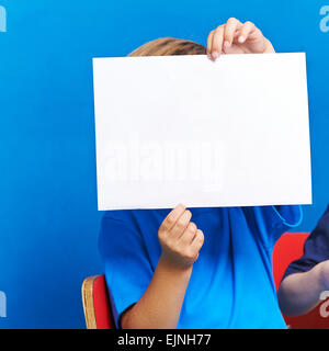 Child showing empty white piece of paper in kindergarten Foto Stock