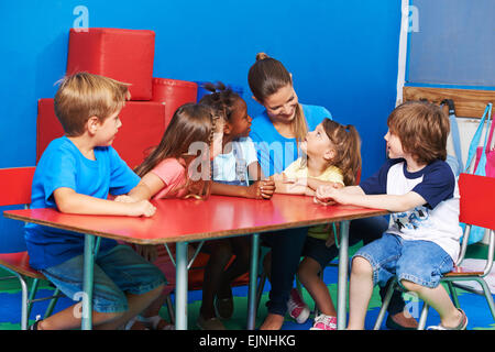 I bambini in circletime listining a ragazza parlando in kindergarten Foto Stock