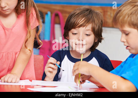 I bambini la pittura di immagini con colori ad acqua in classe d'arte nella scuola elementare Foto Stock