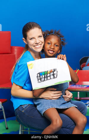 Ragazza e vivaio insegnante mostra di acquarello in kindergarten Foto Stock