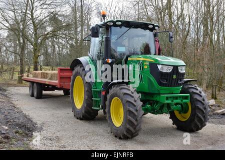 Un John Deere verde e giallo, trattore tirando il rimorchio. Foto Stock