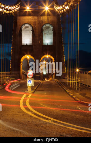 A5 stradale attraverso la sospensione di Menai Bridge con auto sentieri di luce di notte. Percorso storico costruito da Thomas Telford. Bangor Wales UK Foto Stock