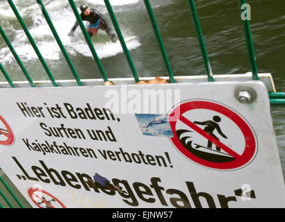 Monaco di Baviera, Germania. 29 Mar, 2015. Un uomo naviga con la sua tavola da surf su un onda nel fiume Eisbach nonostante le avvertenze urgenti da un segno su una barriera che legge 'Il nuoto, surf e kayak vietato - pericolo mortale!' nel Giardino Inglese a Monaco di Baviera, Germania, 29 marzo 2015. Foto: Peter Kneffel/dpa/Alamy Live News Foto Stock