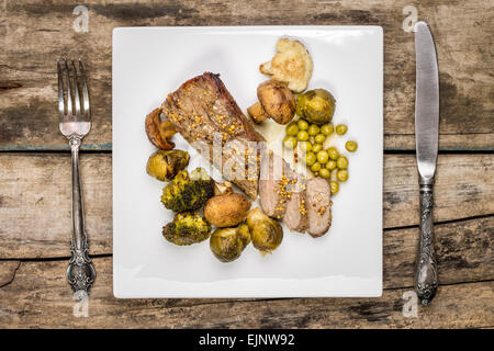 Vista superiore cibo sfondo menu. Arrosto di manzo con verdure cotte con posate sul vecchio tavolo in legno Foto Stock