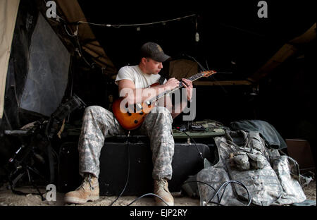 Un U.S. Soldato dell'esercito usa il suo giù il tempo di esercitarsi a suonare la chitarra sul combattimento avamposto Cherkatah, Khowst provincia, Afghanistan, nov. 27, 2009. Il soldato è distribuito con società D, 3° Battaglione, 509a Reggimento di Fanteria. Il personale Sgt. Andrew Smith Foto Stock