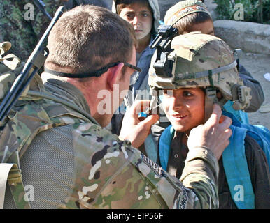 Provincia di Laghman, Afghanistan - STATI UNITI Esercito 2 Lt. Taylor Gingrich, un Ufficiale di fanteria da Cedar Falls, Iowa, con la società A, 1° Battaglione, 133Reggimento di Fanteria, Task Force Ironman, una parte della seconda Brigata Team di combattimento, 34a divisione di fanteria, Task Force Red Bulls, disegna un sorriso da un piccolo ragazzo afghano come Gingrich consente il ragazzo indossare il casco al Quala e' Najil School di Najil gen. 3. I soldati da Co. A., nonché l esercito nazionale afghano soldati dal 1° Company, 1° Battaglione, 201st Reggimento di Fanteria, consegnate forniture donati da persone dalla città di Waverly, Iowa e la sua surroundi Foto Stock