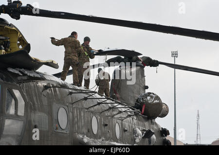 Soldati del primo battaglione, 126Reggimento di aviazione, California Guardia nazionale, Task Force Shadow, a spazzare la neve da un CH-47 elicottero Chinook posteriore della lama del rotore sul 101st combattere la Brigata Aerea linea di volo, Bagram Airfield, Afghanistan, Gennaio 12, 2013. Sgt. Duncan Brennan Foto Stock