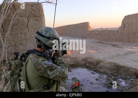 Una delle forze speciali di funzionamento SFODA Detachment-Alpha soldato esegue la scansione della zona come esercito nazionale afghano ANA Commandos, 2 ° società, 3 Operazioni Speciali Kandak SOK condurre il gioco del villaggio Mandozai, Maiwand distretto, provincia di Kandahar, Afghanistan, Dic 27, 2013. La SFODA assistito il 3° SOK nel condurre un gioco di perturbare i ribelli' uso di Mandozai villaggio come un letto basso posizione. Stati Uniti Il personale dell'esercito Sgt. Bertha A. Flores Foto Stock