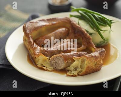 Pasto placcati di rospo nel foro Yorkshire pudding e salsicce con salsa di fagioli verdi e una purea di patate e cavolo verza torta Foto Stock