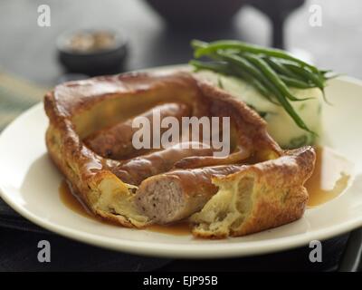 Pasto placcati di rospo nel foro Yorkshire pudding e salsicce con salsa di fagioli verdi e una purea di patate e cavolo verza torta Foto Stock
