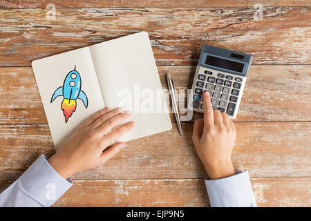 Stretta di mano con la calcolatrice e notebook Foto Stock