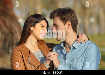 Matura in amore abbracciando e dating seduta su una panchina in un parco alla ricerca di ogni altro Foto Stock