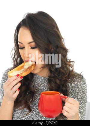 Felice positivo giovane donna godendo di tazza rinfrescante di fresco tè caldo o bevanda di caffè, isolato su bianco, da soli, mangiare toast imburrato Foto Stock