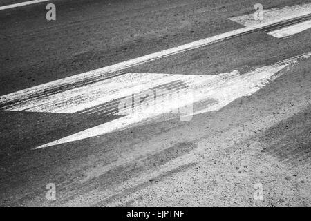 La segnaletica stradale con tracce di pneumatici su asfalto grigio Foto Stock