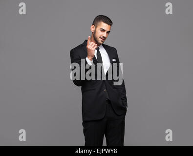 Bello ispanica uomo elegante in abito nero su sfondo grigio Foto Stock