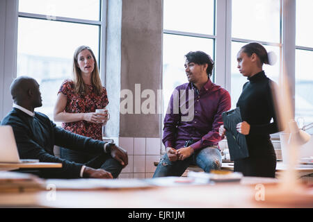 Colpo di diversi team di business a discutere di lavoro in ufficio. Giovani creativi a discutere di un nuovo progetto di business. Foto Stock