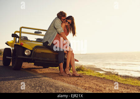 Romantico coppia giovane la condivisione di un momento speciale mentre ci si trova all'esterno. Coppia giovane in amore in un viaggio su strada. Giovane che abbraccia ogni altro Foto Stock