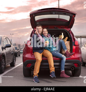 Felice coppia seduta al baule auto dopo lo shopping Foto Stock