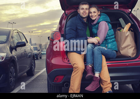 Felice coppia seduta al baule auto dopo lo shopping Foto Stock