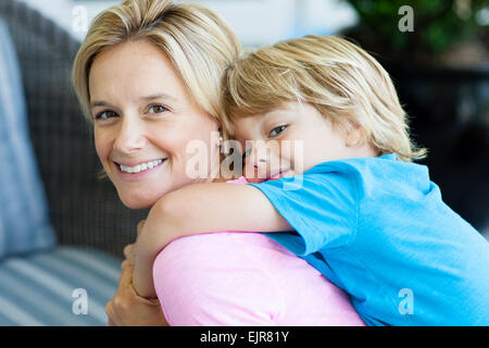 Madre caucasica portando figlio piggyback Foto Stock